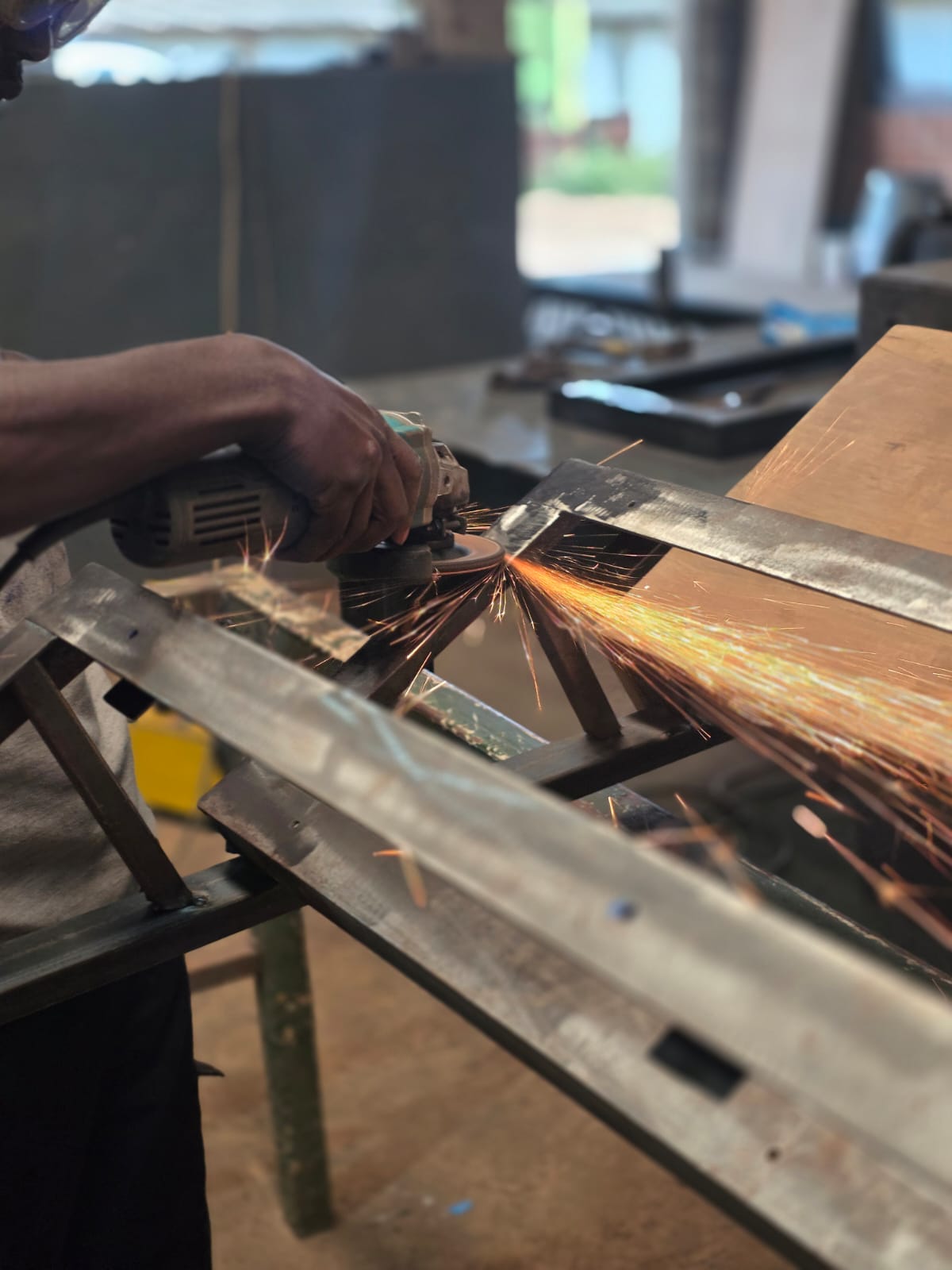 Metalworker grinding a fabricated steel frame, sparks flying