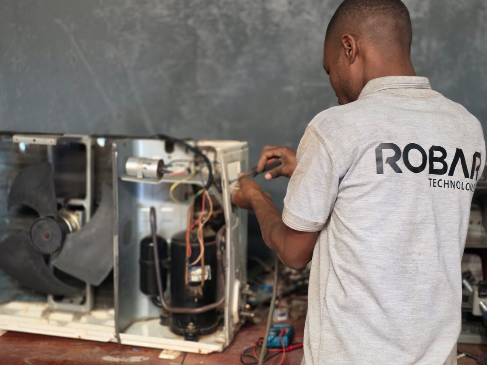 Robar Technologies technician repairing an air-conditioning condenser unit