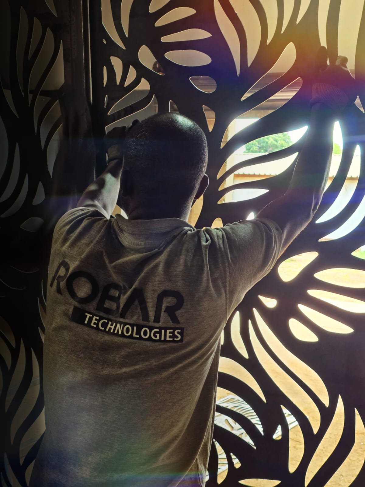 Robar Technologies installer fitting a decorative laser-cut leaf-pattern steel screen