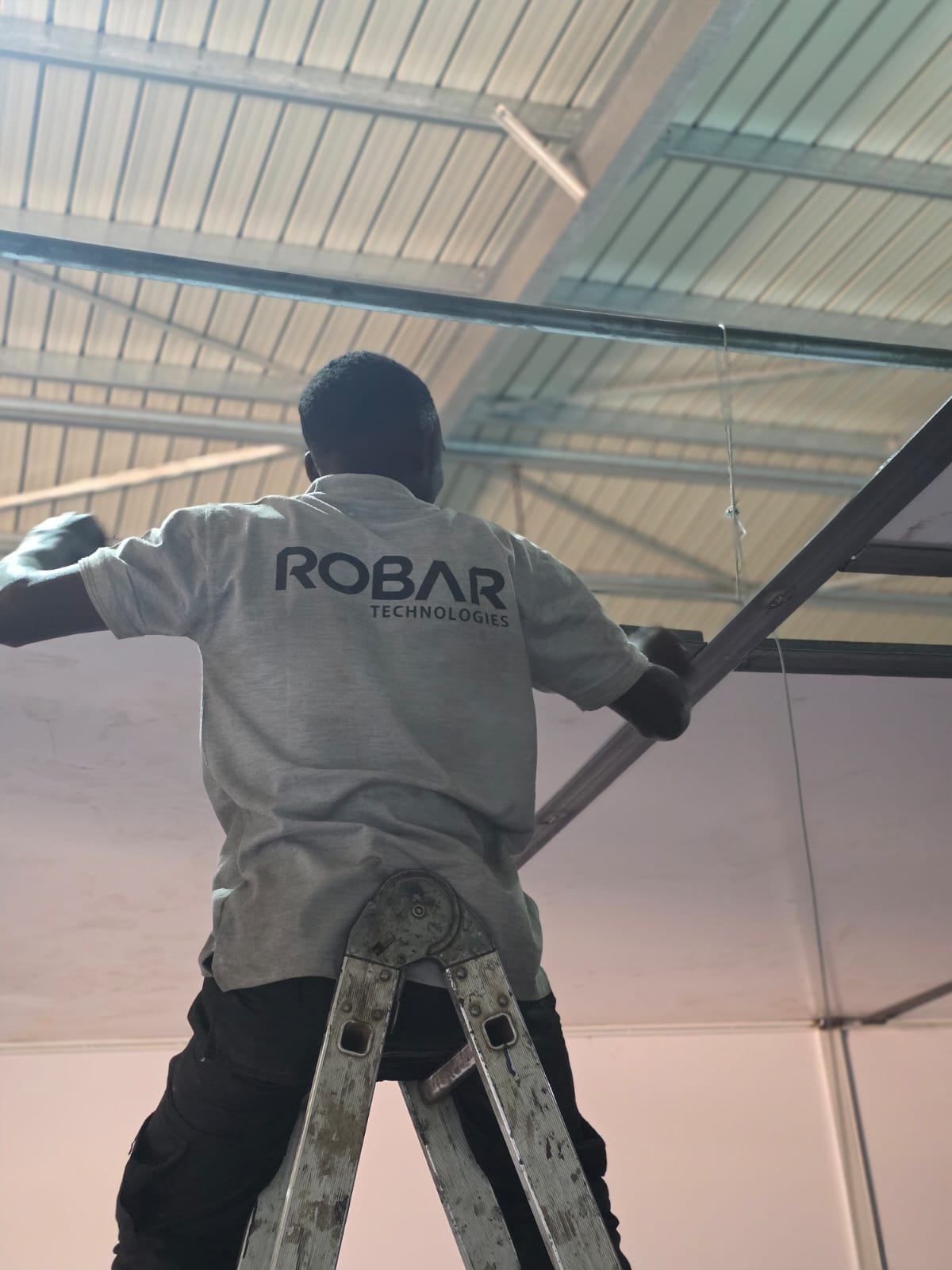 Robar Technologies worker on a ladder installing overhead steel framework