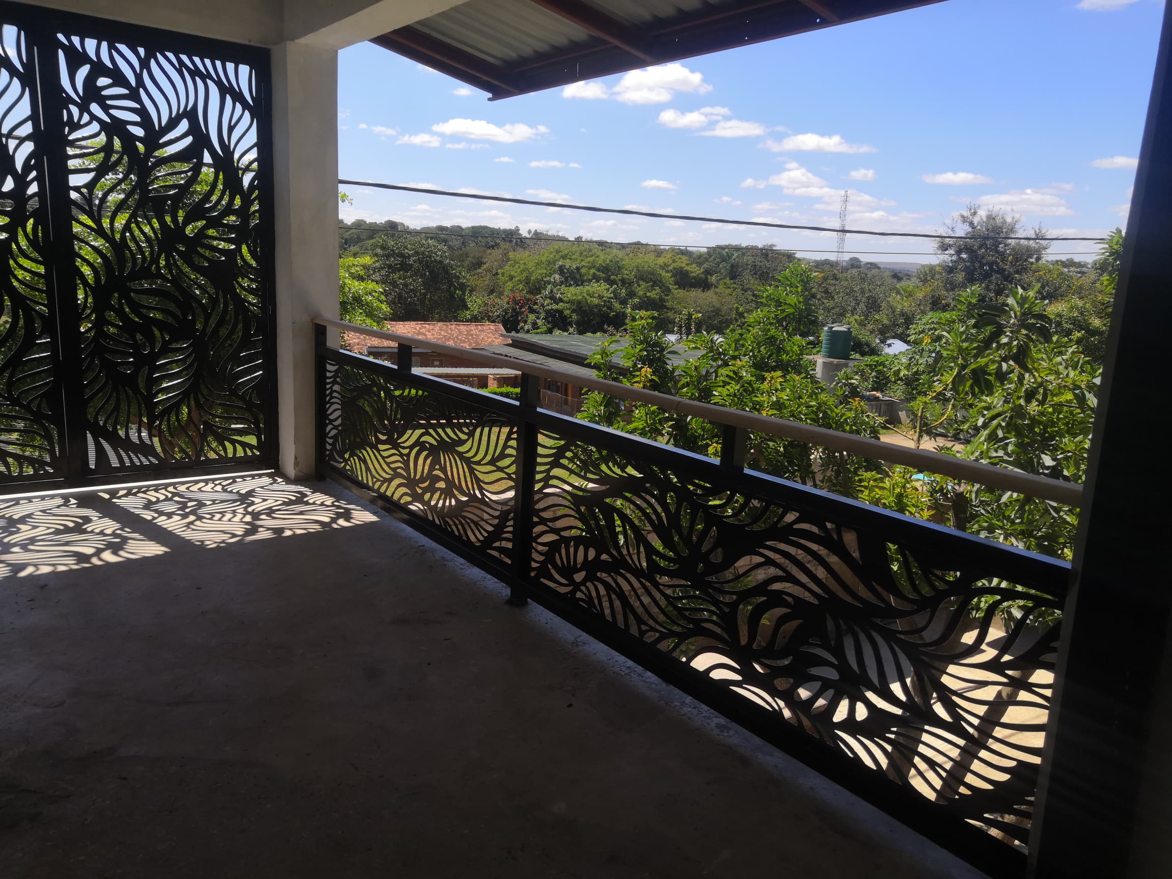 Balcony with a laser-cut leaf-pattern steel balustrade and privacy screen overlooking greenery