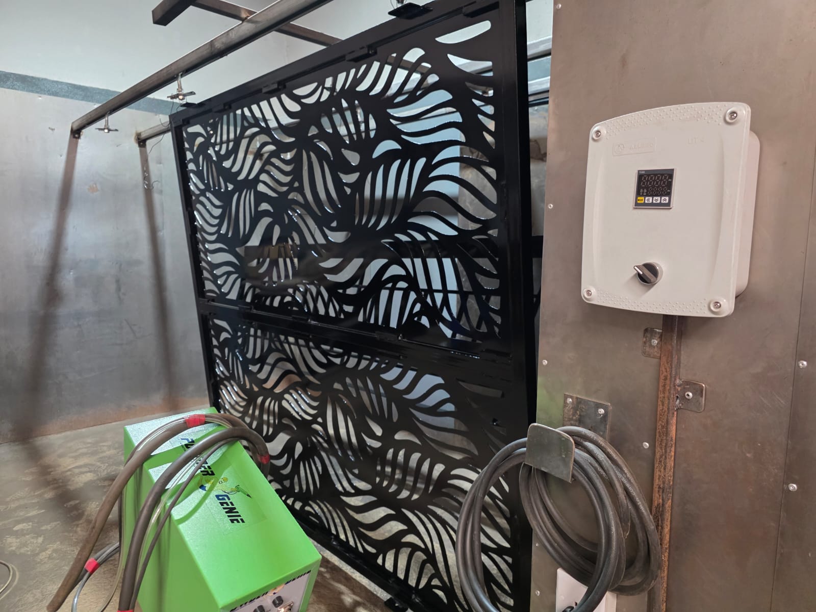 Black powder-coated laser-cut leaf-pattern gate in the coating booth