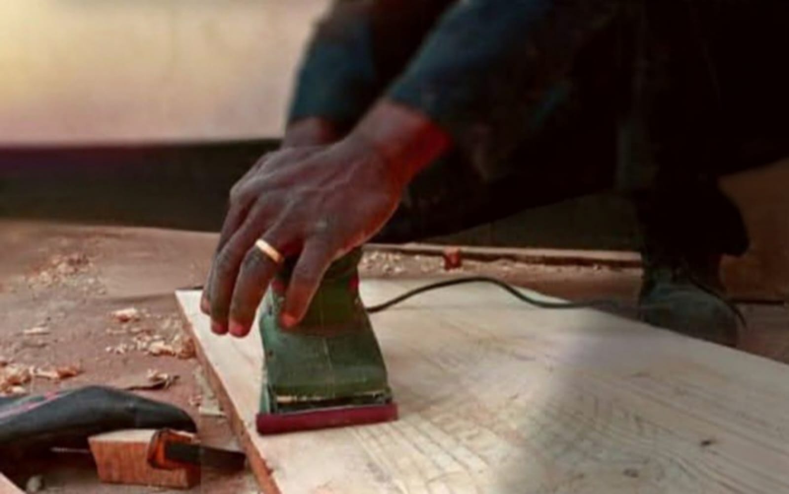 Worker sanding a timber board during renovation finishing