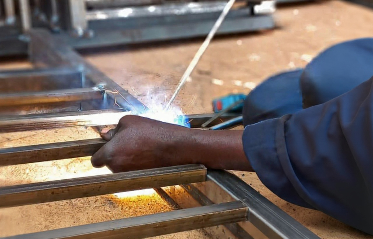 Welder joining a steel frame with a MIG welder, sparks flying