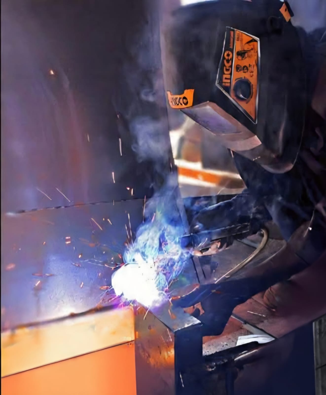 Welder in a mask MIG-welding steel, bright arc light and sparks